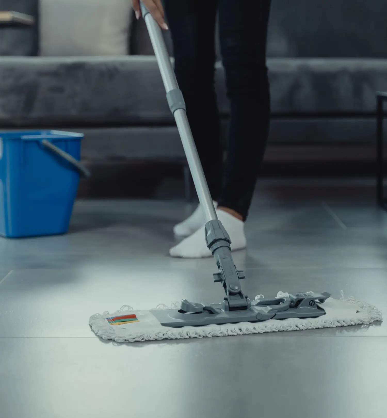 Reinigungsteam in Arbeitskleidung mit Staubsauger und Wischmopp in einem modernen Wohnraum